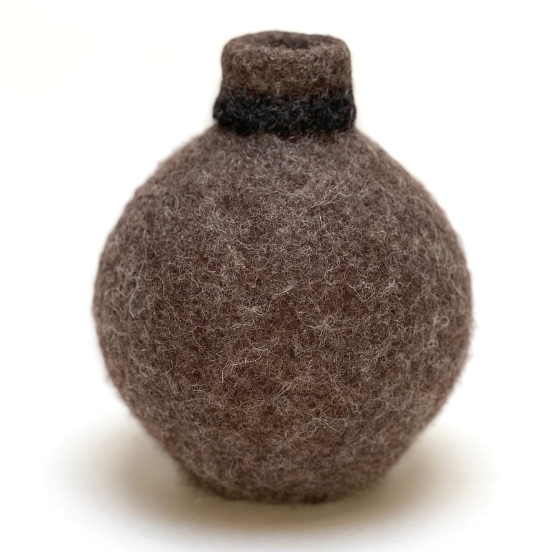 BOLA Black Collar is a small felted urn in undyed brown wool with black trim 