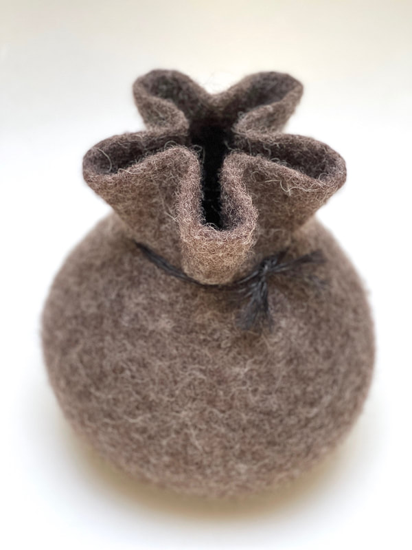 BOLA Gift Wrapped is a medium round shaped felted vessel with a gathered top in brown wool with a black tie